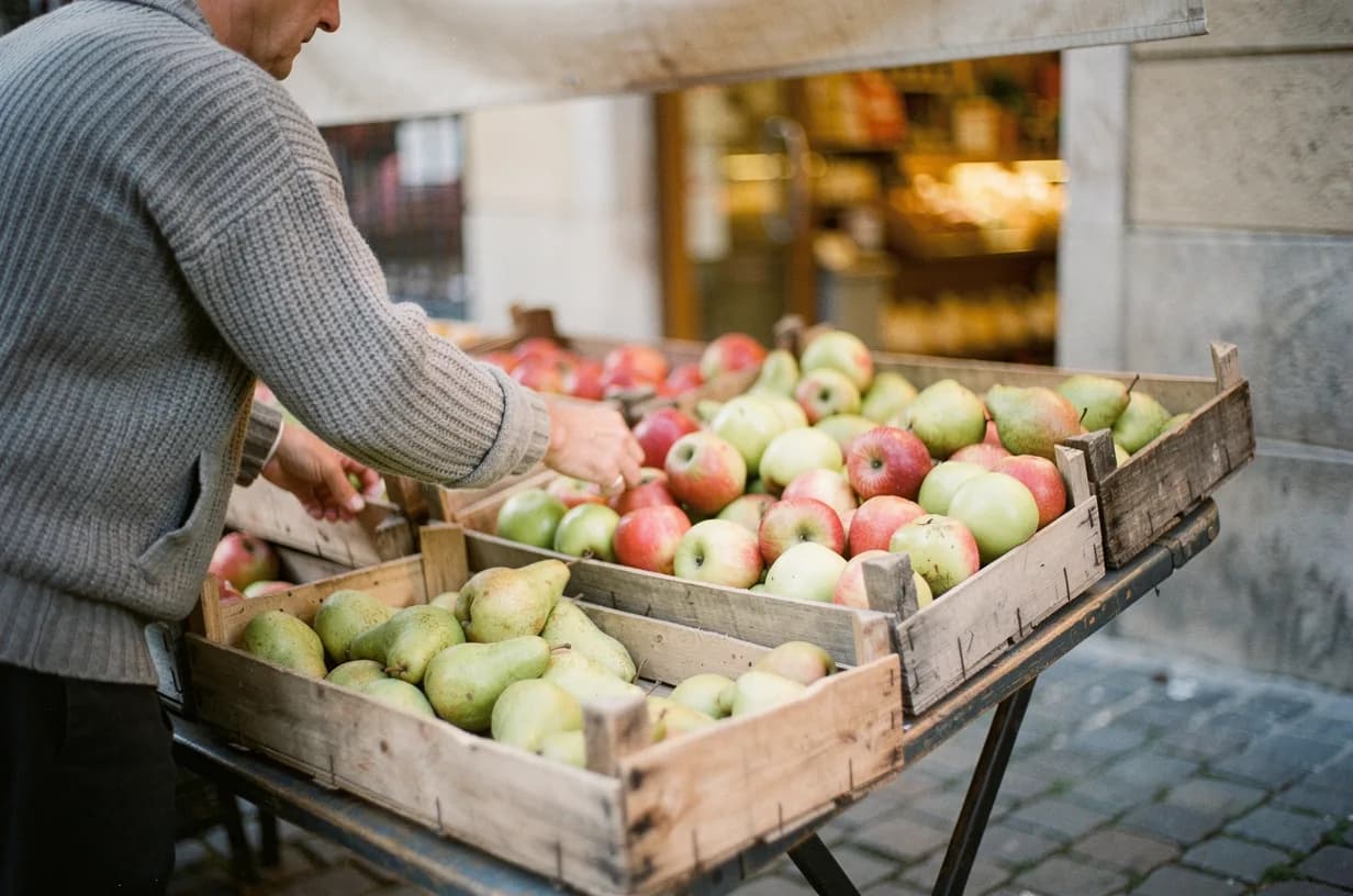 Maraîcher disposant des cageots de pommes et de poires sur l'étal devant sa boutique